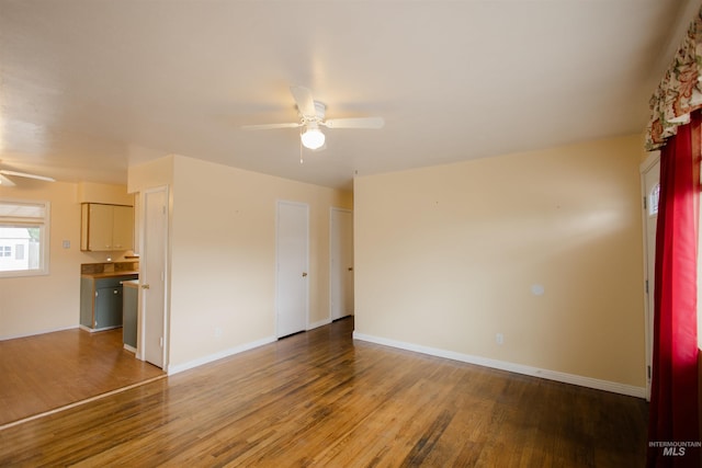 unfurnished room with ceiling fan, wood finished floors, and baseboards