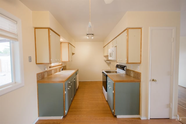 kitchen with electric range, white microwave, a sink, light wood finished floors, and light countertops