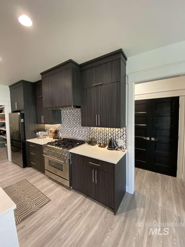 kitchen featuring high end range, light hardwood / wood-style flooring, premium range hood, and fridge