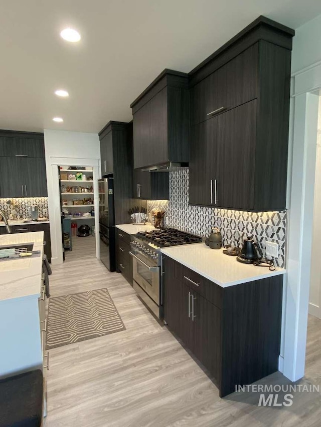 kitchen featuring stainless steel range, refrigerator, light hardwood / wood-style floors, and tasteful backsplash