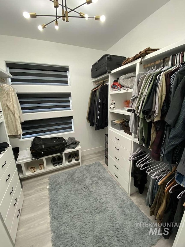 spacious closet with a chandelier and light hardwood / wood-style floors