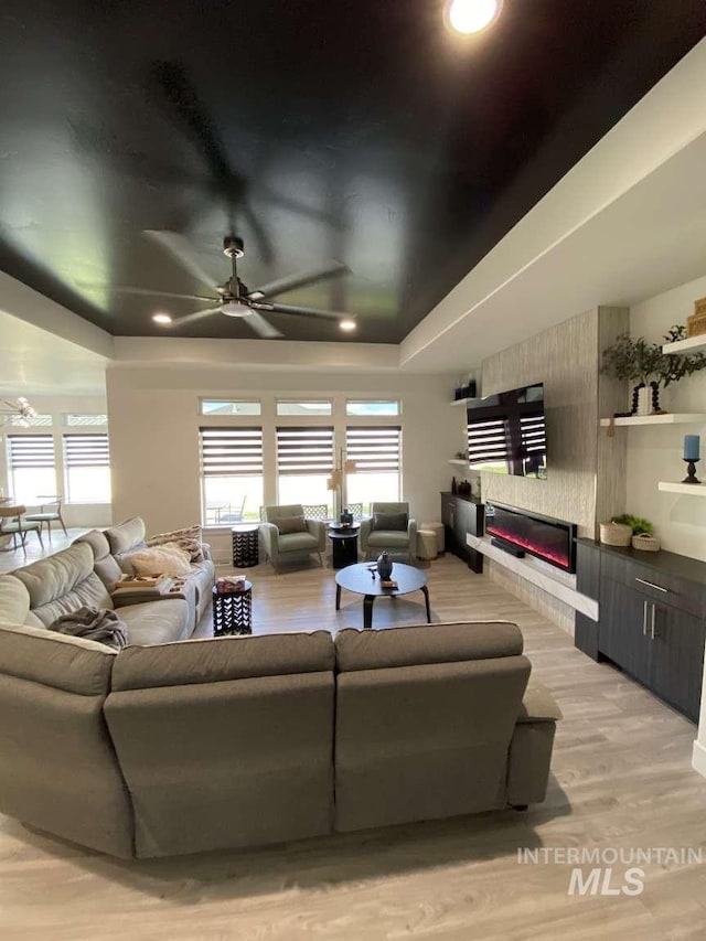 living room with a fireplace, ceiling fan, and light hardwood / wood-style flooring