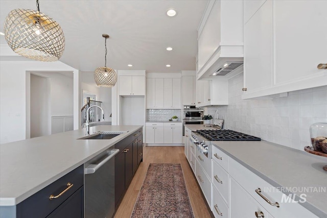 kitchen featuring stainless steel appliances, custom range hood, white cabinetry, and hanging light fixtures