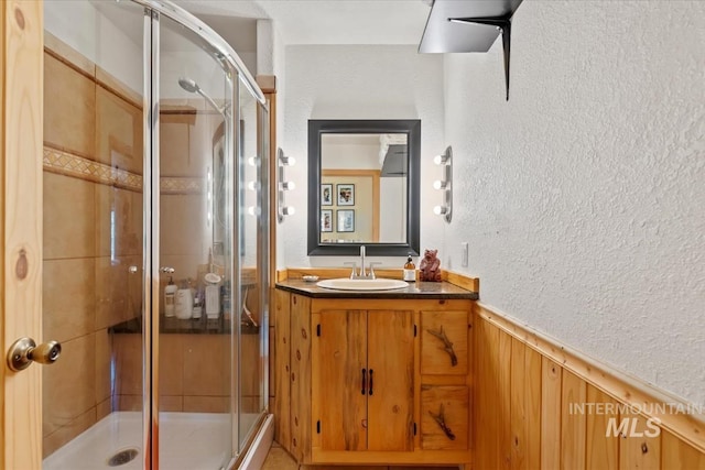 150 W Yuba Vista Dr, Atlanta, ID 83716 - bathroom with wainscoting, a textured wall, vanity, a shower stall, and wooden walls