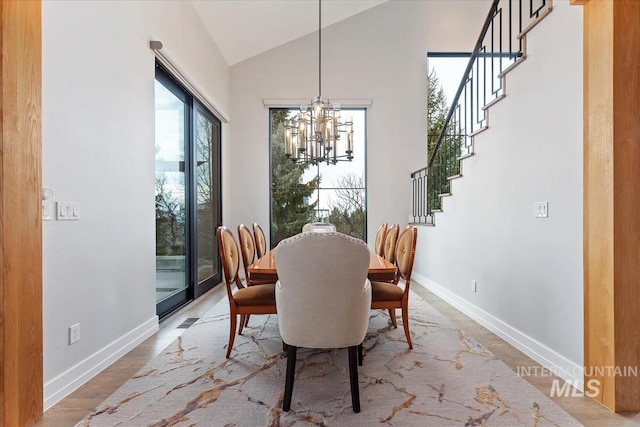 dining room with hardwood / wood-style flooring, lofted ceiling, and a notable chandelier