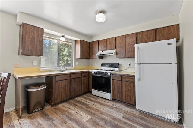 131 Goodall Pl, Mountain Home, ID 83647 - kitchen featuring freestanding refrigerator, gas range, under cabinet range hood, a sink, and light countertops