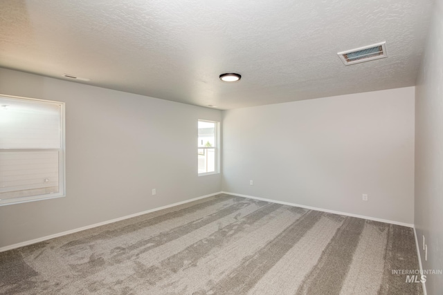 carpeted empty room featuring a textured ceiling