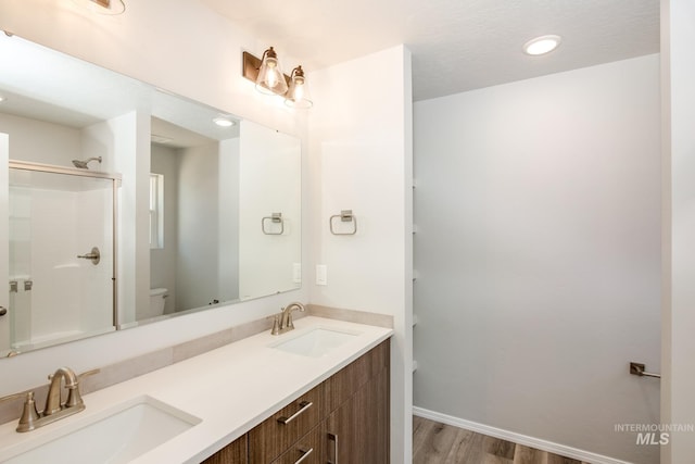 bathroom featuring toilet, an enclosed shower, vanity, and wood-type flooring