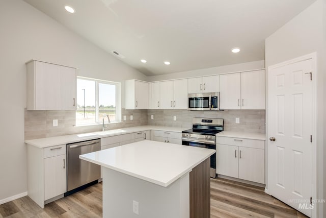 kitchen with white cabinetry, light hardwood / wood-style floors, appliances with stainless steel finishes, and a center island