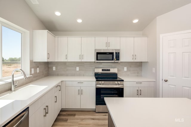 kitchen featuring sink, appliances with stainless steel finishes, white cabinetry, and a healthy amount of sunlight