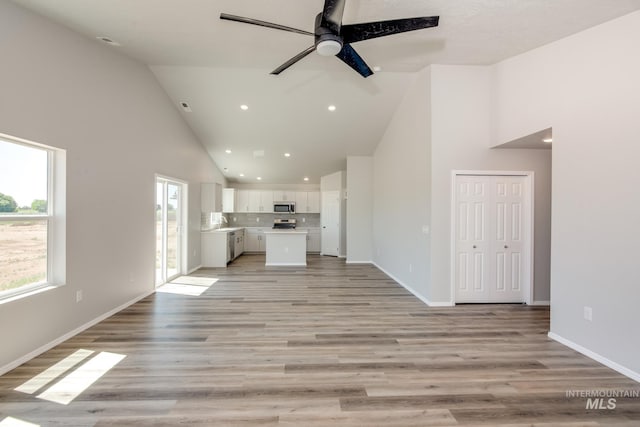 unfurnished living room featuring high vaulted ceiling, light wood-type flooring, and ceiling fan