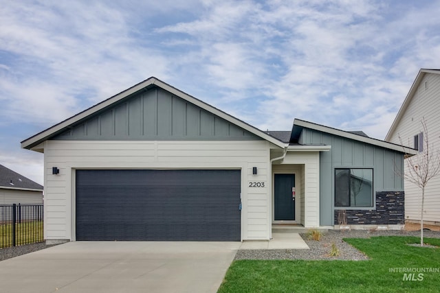 view of front of property with board and batten siding, driveway, an attached garage, and fence