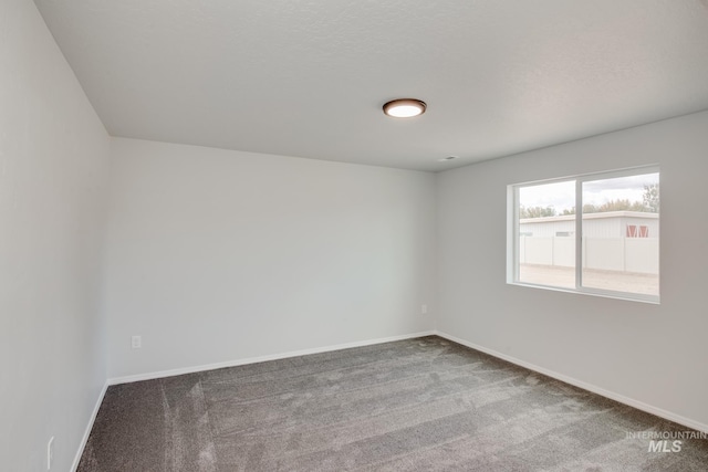 spare room featuring carpet floors, a textured ceiling, and baseboards