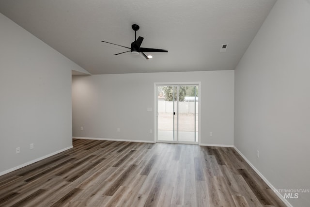 unfurnished room featuring light wood-style floors, visible vents, vaulted ceiling, and baseboards