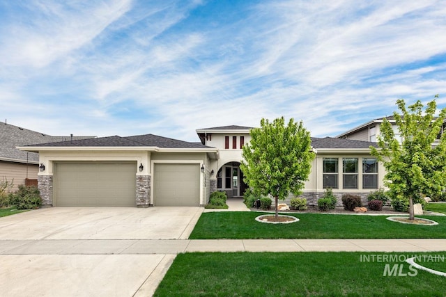 prairie-style home featuring a front yard, a garage, concrete driveway, stone siding, and stucco siding