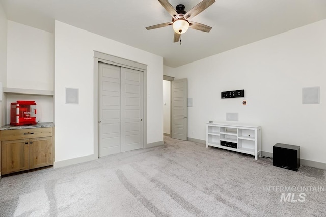 unfurnished bedroom with baseboards, a ceiling fan, a closet, and light colored carpet