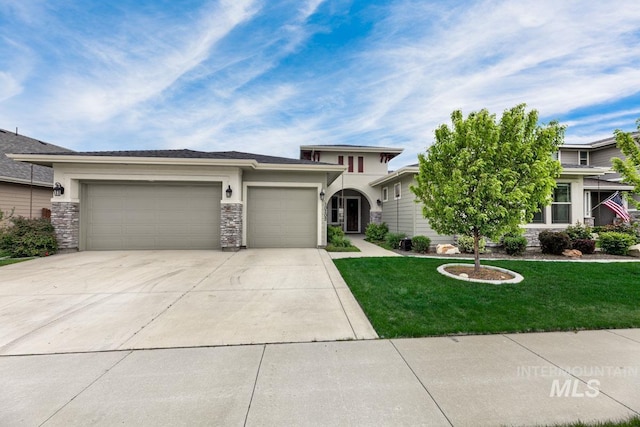 prairie-style house featuring a front lawn, stone siding, a garage, stucco siding, and driveway