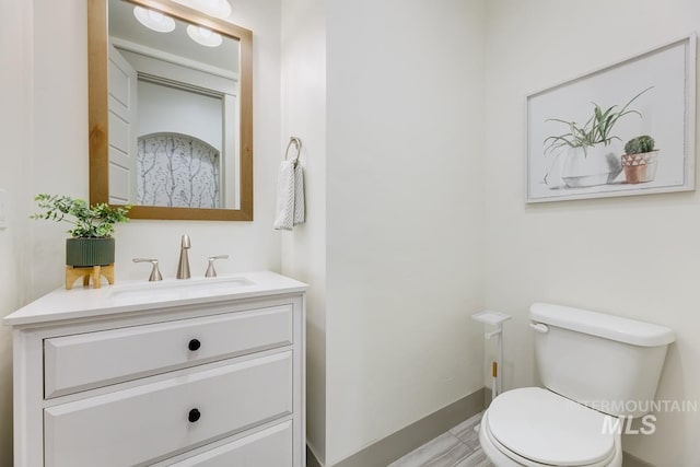 bathroom featuring toilet, baseboards, and vanity