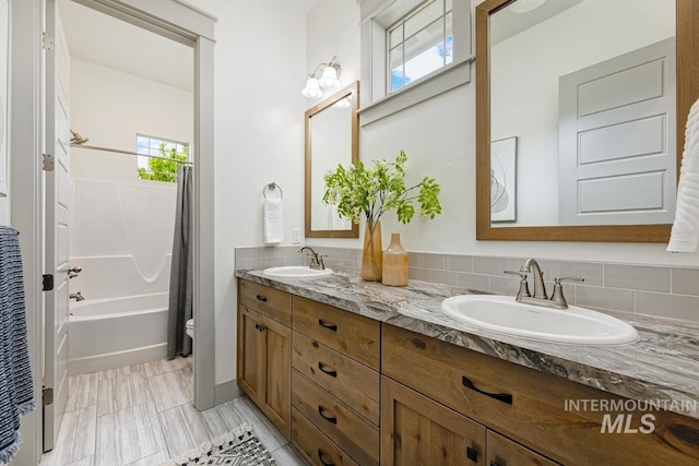 full bathroom featuring a sink, shower / bath combo, toilet, and double vanity