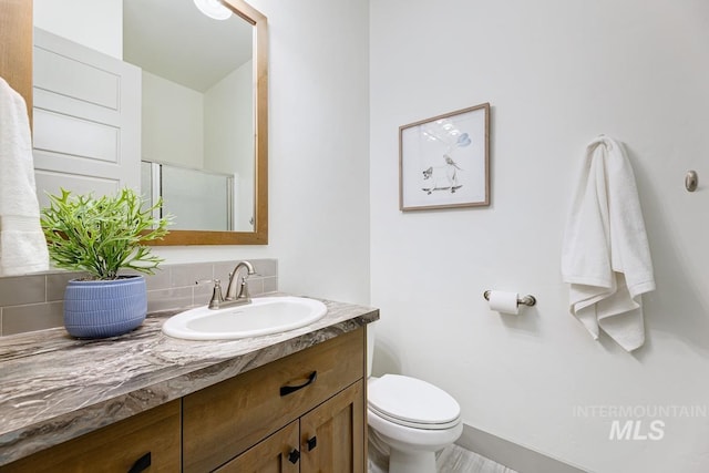full bathroom featuring vanity, baseboards, a stall shower, and toilet