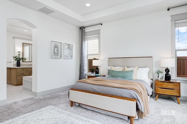 bedroom featuring arched walkways, visible vents, multiple windows, and light colored carpet