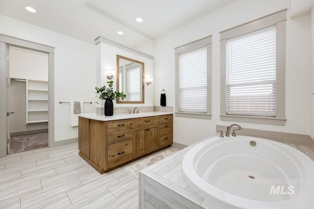 full bathroom featuring a garden tub, recessed lighting, and vanity