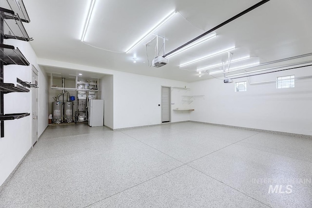 garage featuring freestanding refrigerator, water heater, and a garage door opener