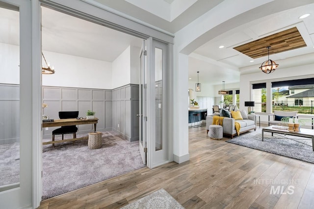 bathroom featuring an inviting chandelier, recessed lighting, a raised ceiling, and wood finished floors