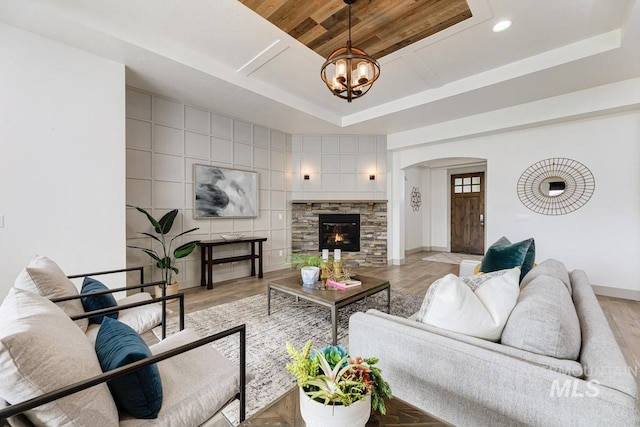 living room featuring arched walkways, wooden ceiling, a raised ceiling, and light wood-style floors