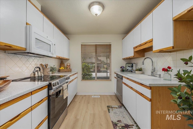 498 E Chester Ln, Boise, ID 83706 - kitchen featuring stainless steel appliances, a sink, decorative backsplash, light wood-type flooring, and light countertops