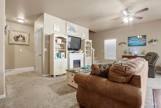 1020 Woodland St, Rupert, ID 83350 - living room featuring light colored carpet, ceiling fan, a glass covered fireplace, and baseboards