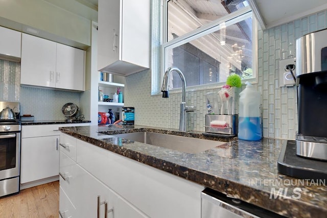937 SW 1st St, Ontario, OR 97914 - kitchen featuring stainless steel appliances, white cabinets, tasteful backsplash, dark stone countertops, and light wood finished floors