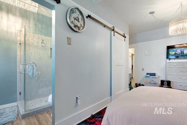 937 SW 1st St, Ontario, OR 97914 - bedroom with a barn door, wood finished floors, a chandelier, and ensuite bath