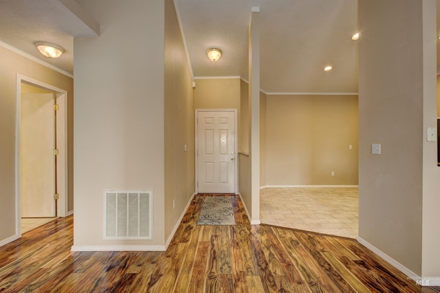 foyer with crown molding, wood finished floors, visible vents, and baseboards