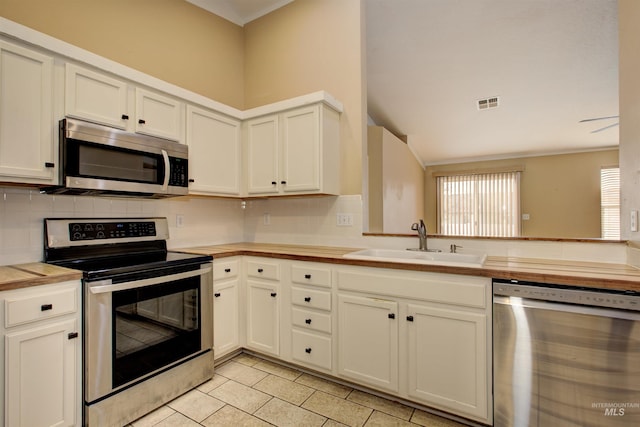 kitchen featuring a sink, appliances with stainless steel finishes, white cabinets, light tile patterned floors, and decorative backsplash