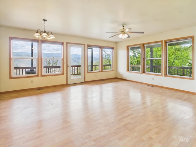 interior space with baseboards, light wood finished floors, and ceiling fan with notable chandelier