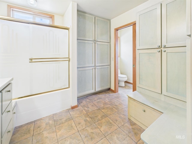 bathroom featuring vanity, shower / bathtub combination, toilet, and stone finish flooring