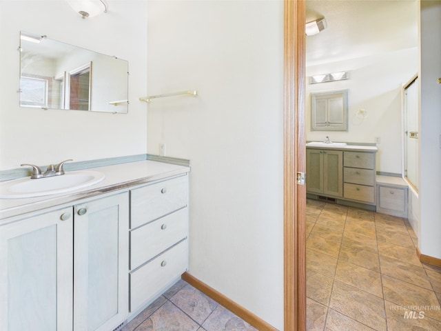 bathroom with a sink, baseboards, and two vanities