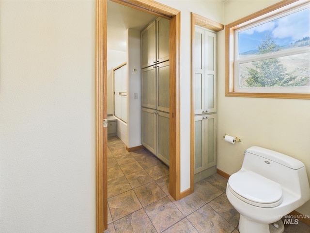 bathroom featuring toilet, baseboards, and walk in shower