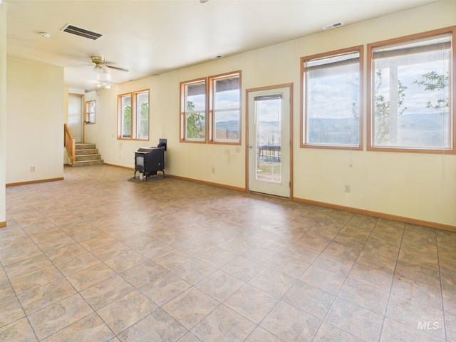 empty room with baseboards, visible vents, ceiling fan, and stairway