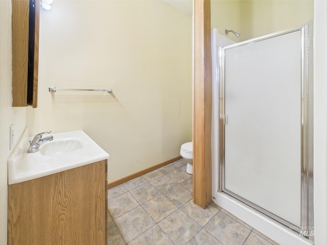 bathroom featuring toilet, baseboards, a shower stall, and vanity