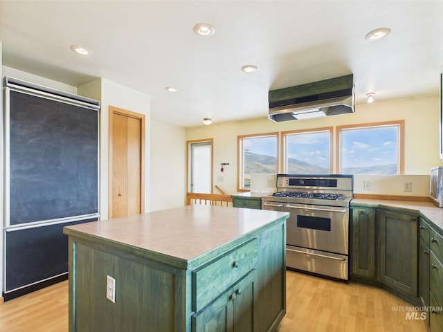 kitchen with a center island, light wood-style flooring, exhaust hood, and range with two ovens