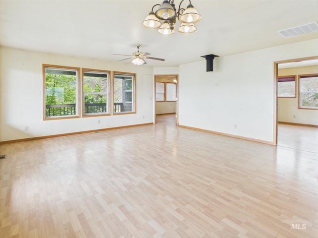 unfurnished living room featuring baseboards, ceiling fan with notable chandelier, light wood-type flooring, and visible vents