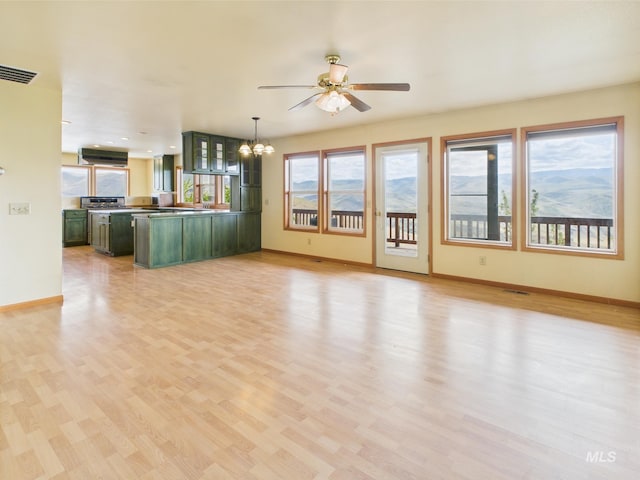 unfurnished living room featuring baseboards, visible vents, ceiling fan with notable chandelier, and light wood-style floors