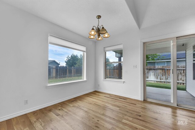 1295 NE Blossom, Mountain Home, ID 83647 - unfurnished dining area featuring a chandelier, wood finished floors, and baseboards