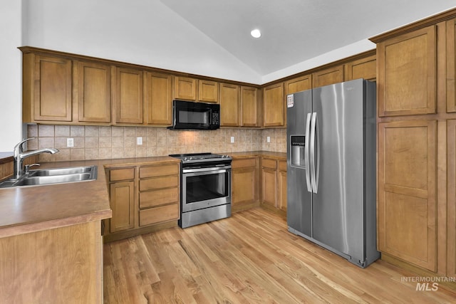 1295 NE Blossom, Mountain Home, ID 83647 - kitchen featuring stainless steel appliances, a sink, lofted ceiling, brown cabinetry, and decorative backsplash