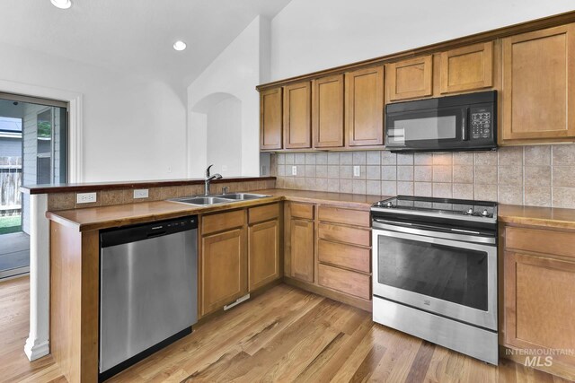 1295 NE Blossom, Mountain Home, ID 83647 - kitchen with appliances with stainless steel finishes, a sink, brown cabinets, tasteful backsplash, and vaulted ceiling