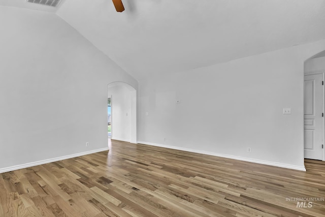 1295 NE Blossom, Mountain Home, ID 83647 - unfurnished living room featuring arched walkways, vaulted ceiling, a ceiling fan, wood finished floors, and baseboards