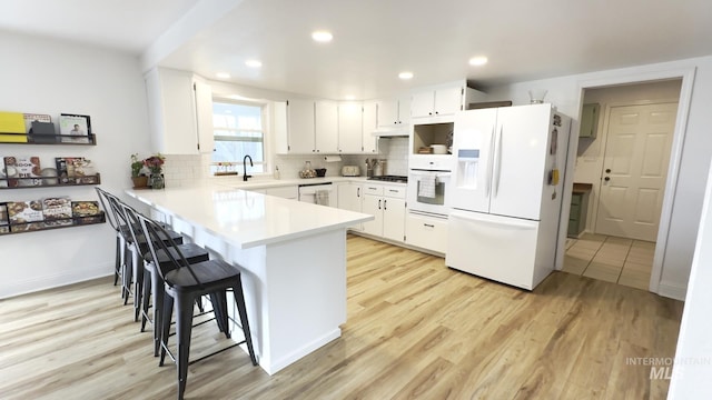 7985 S Cloverdale Rd, Boise, ID 83709 - kitchen featuring a sink, white appliances, light wood-style floors, a peninsula, and a kitchen bar