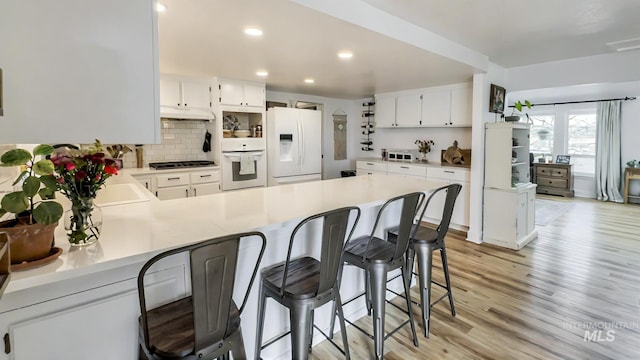 7985 S Cloverdale Rd, Boise, ID 83709 - kitchen featuring decorative backsplash, a peninsula, white appliances, and light countertops